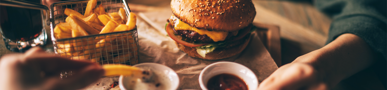 Photo vu du dessus d'un plateau de nourriture contenant un burger, une petite panier de frite et des sauciers