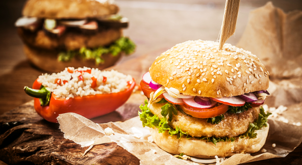 Photo d'un burger sur une planche accompagné d'un poivron garni.